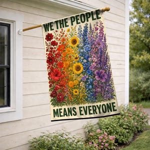 May include: A rectangular garden flag featuring a rainbow-colored floral arrangement with red, orange, yellow, blue, and purple flowers. The text WE THE PEOPLE is printed in dark green at the top, and MEANS EVERYONE is printed in dark green at the bottom.