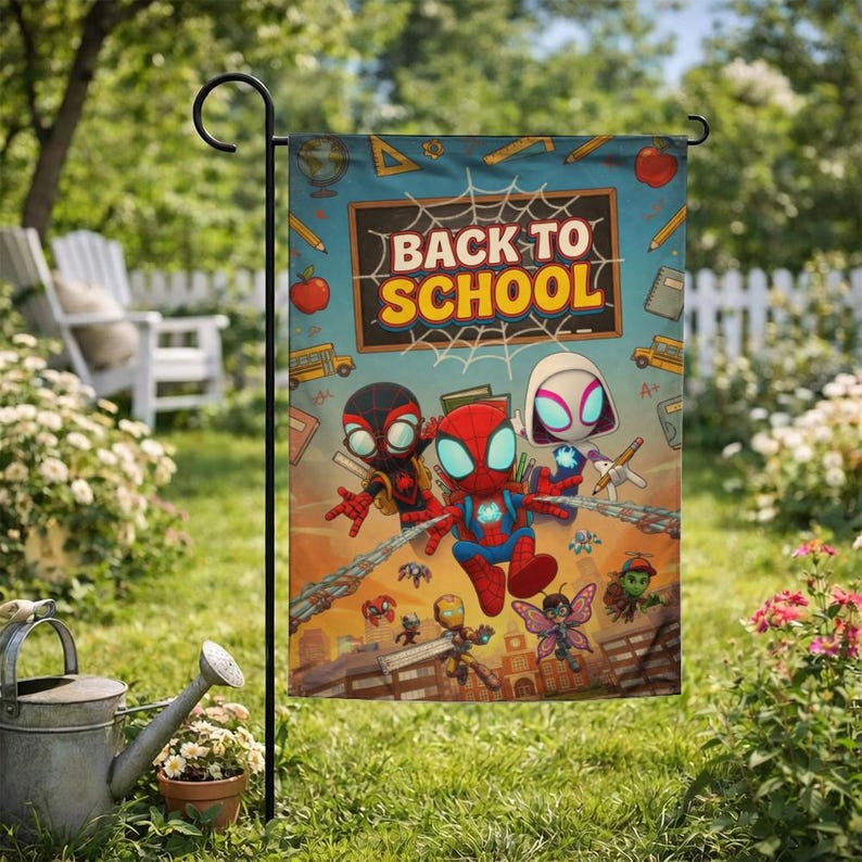 Puede incluir: Bandera de jard&iacute;n con una colorida ilustraci&oacute;n de personajes de Spider-Man y el texto "BACK TO SCHOOL". La bandera est&aacute; sujeta a un poste de metal negro, con c&eacute;sped verde, flores y una valla blanca.