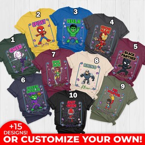May include: A selection of superhero t-shirts in diverse colours, each showcasing a different character such as Spider-Man, Hulk, and Black Panther. The shirts display character names and graphics within a spiderweb design. The bottom text reads "+15 DESIGNS! OR CUSTOMIZE YOUR OWN!"