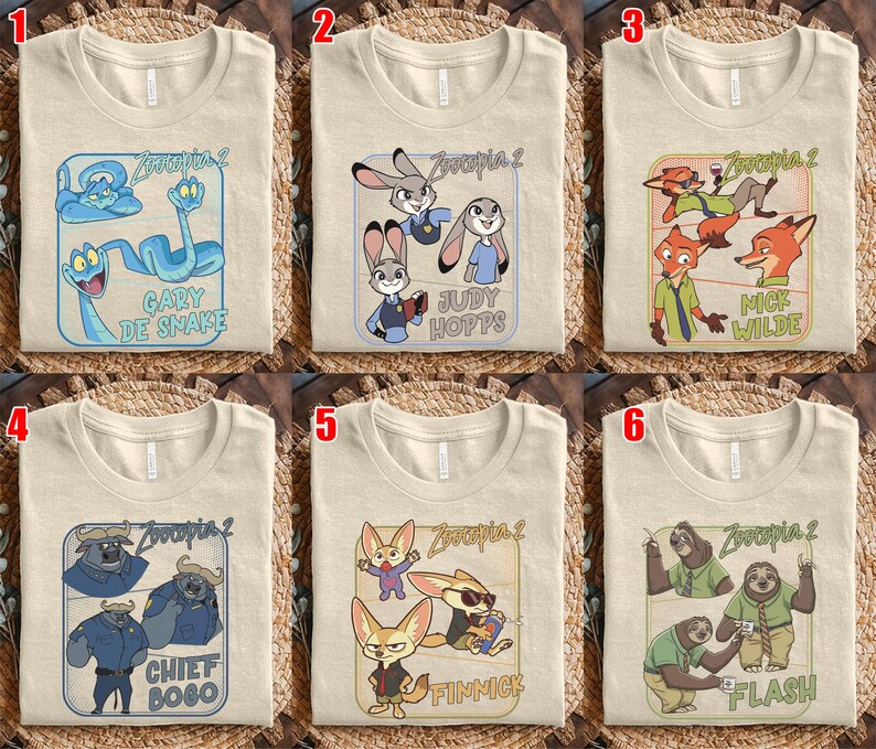 Pode incluir: Seis camisetas bege com diferentes designs de personagens de Zootopia 2. Cada camisa apresenta um gr&aacute;fico retangular com personagens como Gary De Snake, Judy Hopps, Nick Wilde, Chief Bogo, Finnick e Flash.