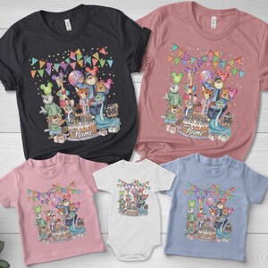 May include: A collection of t-shirts and a onesie in various colors, featuring a colorful cartoon design. The design includes a birthday cake, cartoon characters, balloons, and the word "Name". The shirts are in black, pink, and blue.
