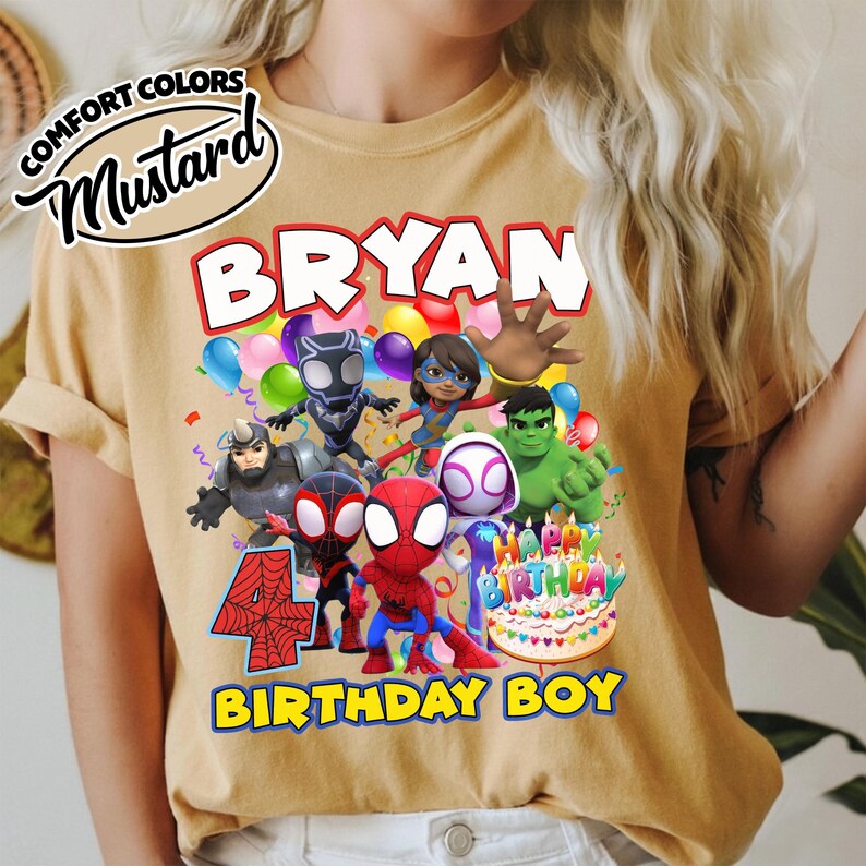May include: A mustard yellow t-shirt featuring a graphic print of Marvel superheroes including Spider-Man, Hulk, and Black Panther. The design includes the text BRYAN, the number 4 with a spiderweb pattern, a birthday cake, and BIRTHDAY BOY.