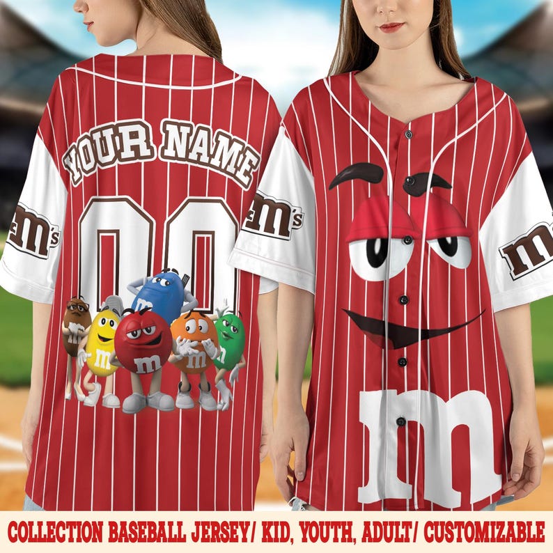 Puede incluir: Camiseta de b&eacute;isbol roja y blanca con rayas verticales. La camiseta tiene el texto "YOUR NAME" sobre el n&uacute;mero "00" en la espalda. La parte delantera muestra un gran dise&ntilde;o de personaje de M&M's. Las mangas son blancas con el logo de M&M's.