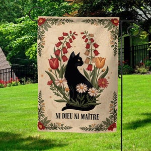 May include: A garden flag featuring a black cat surrounded by flowers in shades of red, orange, and white. The flag has the text "NI DIEU NI MAÎTRE" at the bottom, with a decorative floral border.