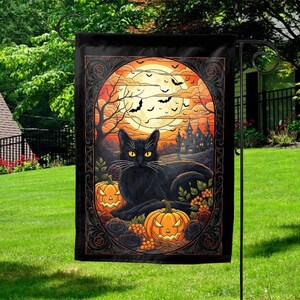 May include: A Halloween garden flag featuring a black cat with yellow eyes, lying in front of two carved pumpkins. The background includes a full moon, bats, a spooky castle, and bare trees, all framed by an ornate border.