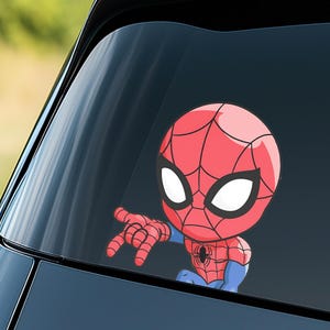 Pode incluir: Um autocolante de desenho animado do Homem-Aranha, com um esquema de cores vermelho e azul. O autocolante mostra a cabe&ccedil;a e o bra&ccedil;o do Homem-Aranha, com a m&atilde;o estendida. O autocolante foi concebido para ser colocado no vidro de um carro.