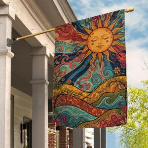 May include: A colorful outdoor flag featuring a smiling sun with closed eyes, radiating warmth. The design includes swirling patterns, flowers, and waves in shades of orange, blue, and green. The flag is hanging from a gold-colored pole.