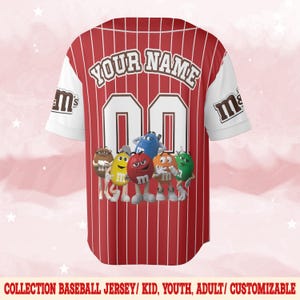 Puede incluir: Camiseta de b&eacute;isbol roja y blanca con rayas verticales rojas. La camiseta presenta el texto "YOUR NAME" sobre el n&uacute;mero "00" y un grupo de personajes de dibujos animados de M&M's. Las mangas son blancas con el logo "M&M's".