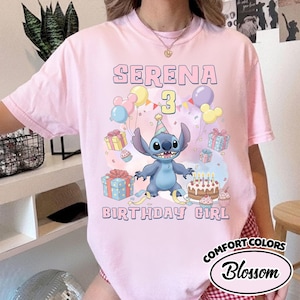 Peut inclure: Un t-shirt rose clair avec une illustration du personnage Stitch portant un chapeau de f&ecirc;te, entour&eacute; de ballons color&eacute;s, de cadeaux, d'un g&acirc;teau d'anniversaire et de confettis. Le texte indique SERENA 3 BIRTHDAY GIRL en bleu clair.
