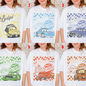 May include: White t-shirts featuring cartoon car characters. Each shirt has a different character design with text including names like "Luigi", "Sally", "Doc", "Chick Hicks", "Mack", and "Mater", along with the year "2006" and the word "Rusteze".