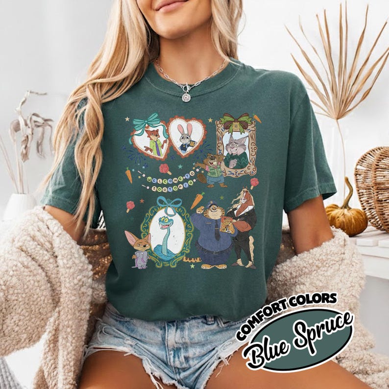 May include: A dark green t-shirt featuring a graphic print of various animated animal characters from Zootopia, including a fox, rabbit, and sloth, arranged in decorative frames with the text Welcome to Zootopia and small carrot illustrations.