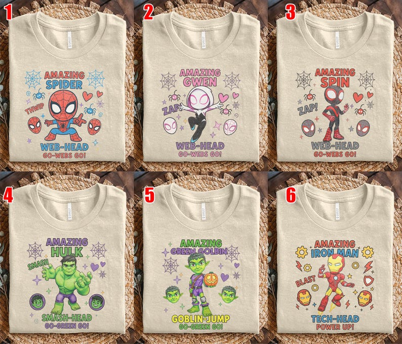 May include: Six beige t-shirts with superhero designs. Each shirt features a different character: Spider-Man, Spider-Gwen, Spider-Man (Miles Morales), Hulk, Green Goblin, and Iron Man. Each design includes the character's name and related phrases.