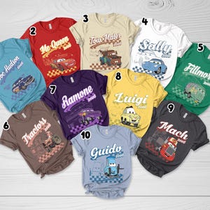 May include: A collection of ten short-sleeved t-shirts in various colors, each featuring a character from the movie Cars with their name, the year 2006, and a checkered flag graphic. The shirts are numbered one through ten and display characters including Doc Hudson, Mc Queen, Tow Mater, Sally, Fillmore, Tractors, Ramone, Luigi, Mach, and Guido.