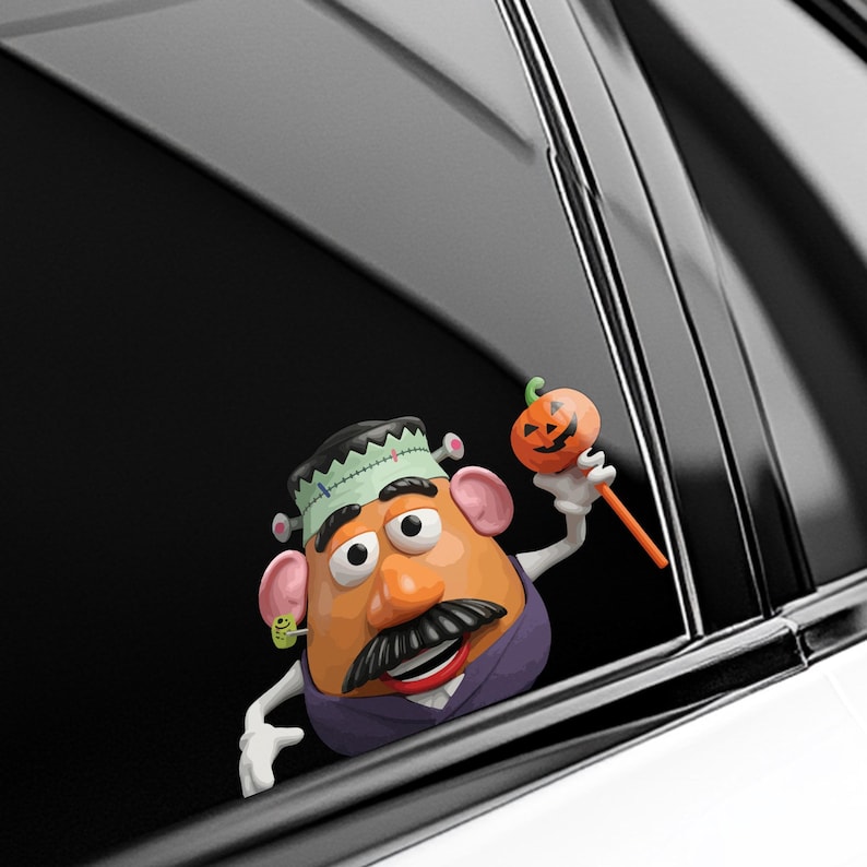 May include: A Halloween car window sticker featuring a Mr. Potato Head character dressed as Frankenstein. The character holds an orange pumpkin lollipop. The decoration has a black, white, orange, green, and purple colour scheme.