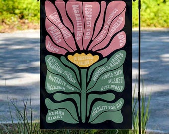 May include: A black garden flag with a floral design featuring various words in white and green, including "Love is Love," "Diversity and Inclusion," and "Equality for All." The flag also includes the text "In this house we believe in."