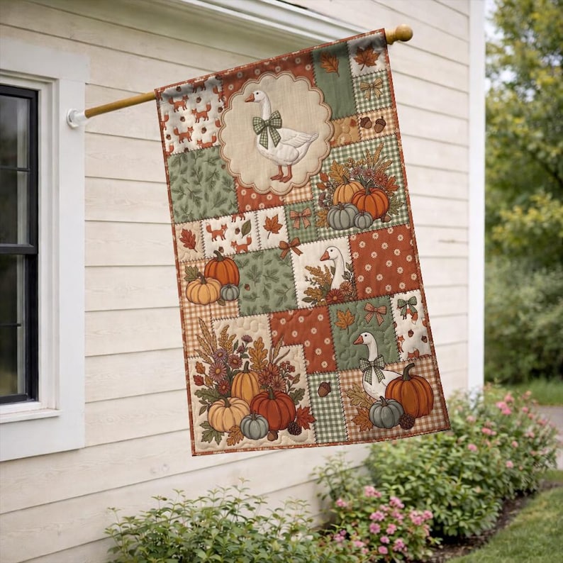 Pu&ograve; includere: Una bandiera da giardino rettangolare con un design patchwork a tema autunnale. La bandiera mostra illustrazioni di oche bianche con fiocchi verdi, zucche arancioni e verdi, ghiande e foglie autunnali nei toni del marrone, dell'arancione e del verde.