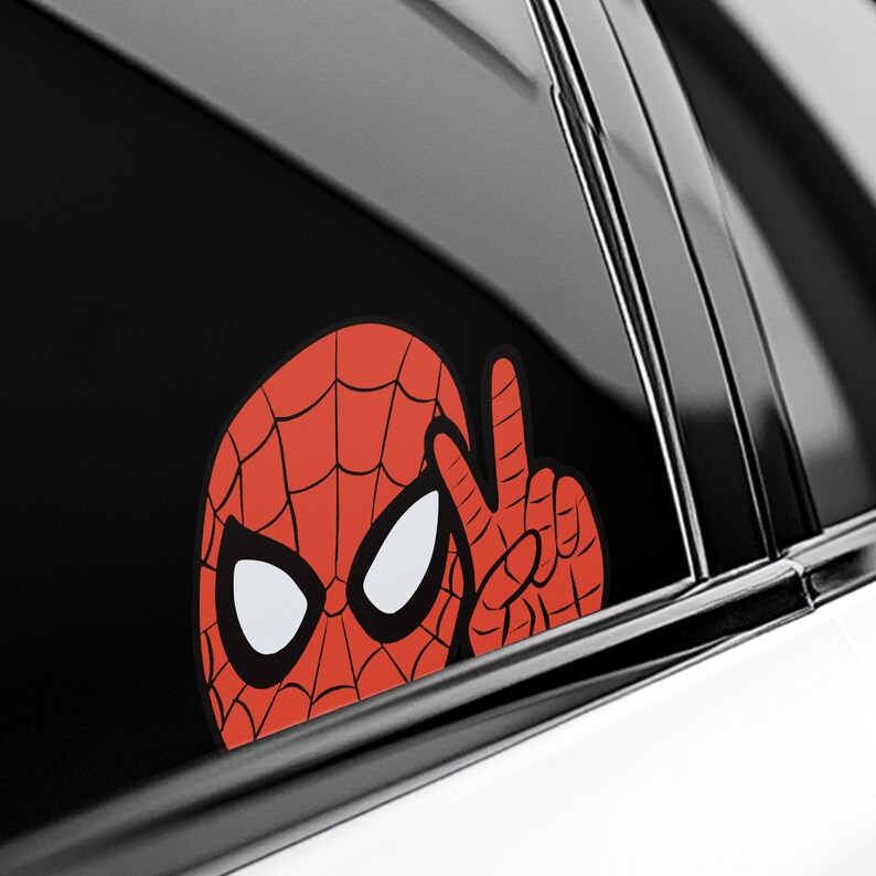 Pu&ograve; includere: Un adesivo per auto di Spider-Man rosso e nero. L'adesivo mostra la testa e la mano di Spider-Man che fanno il segno della pace. L'adesivo &egrave; su un finestrino dell'auto.