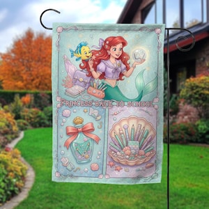 Puede incluir: Una bandera de jard&iacute;n decorativa con una ilustraci&oacute;n de sirena con cabello rojo y cola verde, sosteniendo un orbe brillante. La bandera tiene un fondo azul claro con el texto "PRINCESS BACK TO SCHOOL". El dise&ntilde;o incluye &uacute;tiles escolares y una concha.