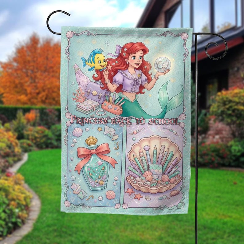 Puede incluir: Una bandera de jard&iacute;n decorativa con una ilustraci&oacute;n de sirena con cabello rojo y cola verde, sosteniendo un orbe brillante. La bandera tiene un fondo azul claro con el texto "PRINCESS BACK TO SCHOOL". El dise&ntilde;o incluye &uacute;tiles escolares y una concha.