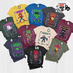 May include: Ten brightly coloured t-shirts, each showcasing a different superhero. The designs include characters like Spider-Man, Hulk, and Iron Man, with their names and associated imagery. The shirts are laid out on a flat surface, ready for display.