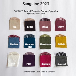 May include: A fabric swatch display labeled "Sanguine 2023" with twelve color samples. Colors include Tan, Coffee, Mauve, Sherry, Blue Jean, Moroccan Blue, Moss Green, Old Gold, Ivory, Plum, Rasberry, and Charcoal. The fabric is a blend of Tencel, Organic Cotton, and Spandex.
