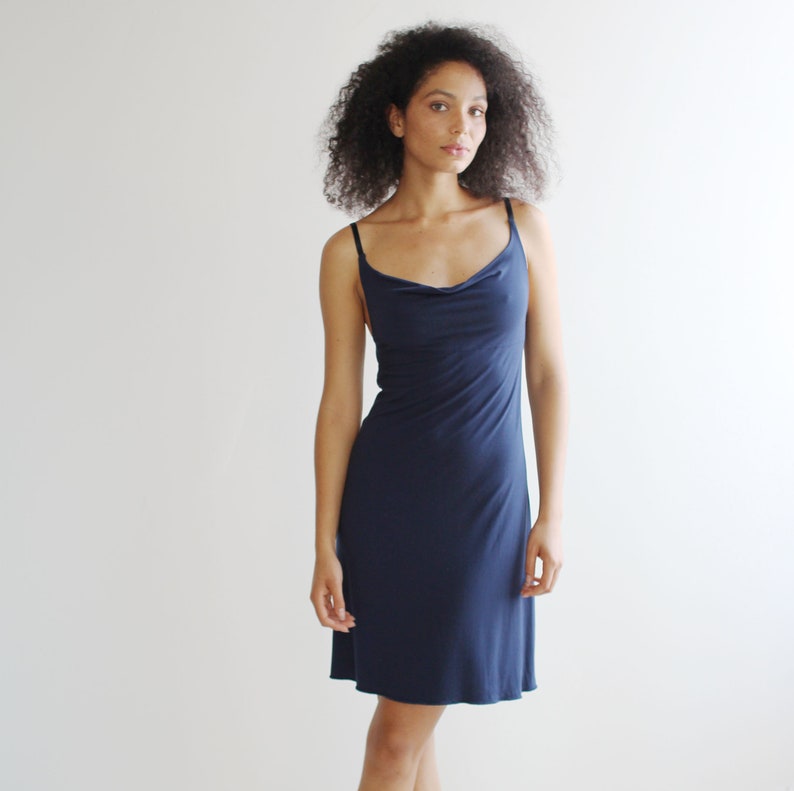 May include: A navy blue sleeveless dress with a cowl neck and a fitted silhouette.