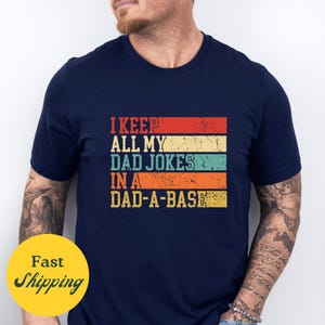 Könnte beinhalten: Ein marineblaues T-Shirt mit einer Grafik im Vintage-Stil, auf dem "Ich behalte all meine Papa-Witze in einer Papa-Datenbank" steht.