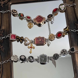 May include: Three silver charm bracelets with different colored watch faces and charms. The charms include a heart, cross, flower, and skull.