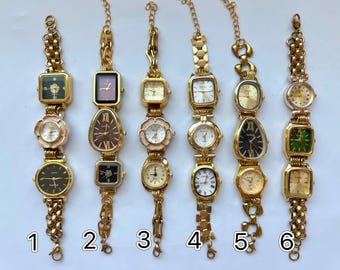 May include: A collection of six vintage gold-toned wristwatches with various face shapes, including square, rectangular, and floral designs. Each watch features a different colored face and is connected by a gold chain bracelet.