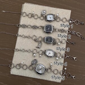 May include: Five silver watch bracelets with different charms and styles. The bracelets are on a white surface. The styles are labeled "style 1" through "style 5".