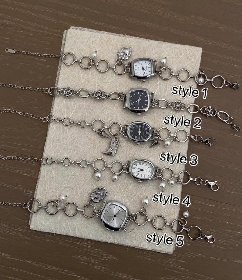 May include: Five silver watch bracelets with different charms and styles. The bracelets are on a white surface. The styles are labeled "style 1" through "style 5".
