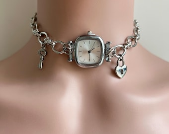 May include: A silver choker necklace with a square watch, a key charm, and a heart-shaped padlock charm.