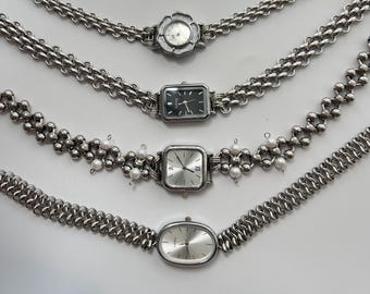 May include: Four silver chain link bracelets with different watch faces. The watches have silver bands and round, square, and oval faces.