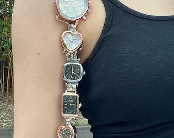 May include: A gold chain with multiple watch faces attached. The watches are in different shapes and sizes, including round, square, and heart-shaped. The chain is worn over a person's shoulder.