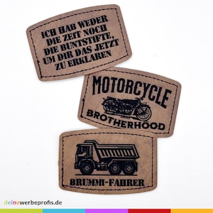 Könnte beinhalten: Drei braune Lederpatches mit schwarzem Text und Bildern. Der erste Patch sagt "ICH HAB WEDER DIE ZEIT NOCH DIE BUNTSTIFTE, UM DIR DAS JETZT ZU ERKLAREN". Der zweite Patch sagt "MOTORCYCLE BROTHERHOOD" und hat ein Schwarzweißbild eines Motorrads. Der dritte Patch sagt "BRUMMI-FAHRER" und hat ein Schwarzweißbild eines Kipplastwagens.