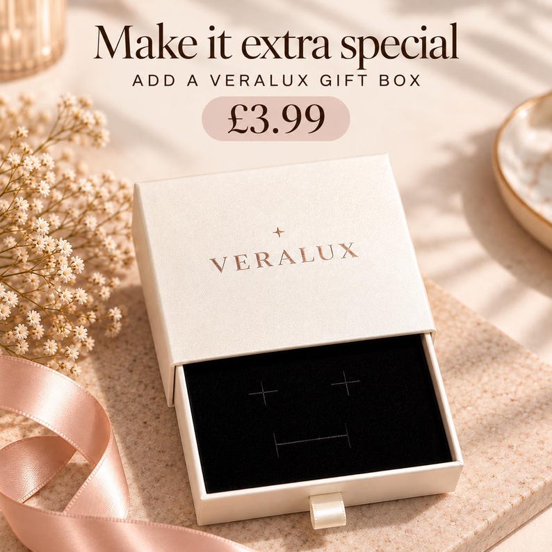 May include: A square, cream-colored jewelry gift box with a sliding drawer mechanism. The lid features the text 'Make it extra special', 'ADD A VERALUX GIFT BOX', and the brand name 'VERALUX' with a small star icon. The interior has a black velvet insert.