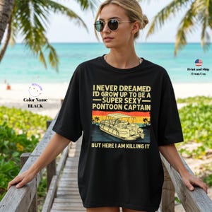 K&ouml;nnte beinhalten: Schwarzes T-Shirt mit dem Text "I NEVER DREAMED I'D GROW UP TO BE A -SUPER SEXY- PONTOON CAPTAIN BUT HERE I AM KILLING IT" und einer Grafik eines Pontonboots. Die Person tr&auml;gt eine Sonnenbrille.