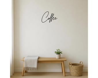 May include: A minimalist interior scene featuring a wooden bench with a light-colored throw blanket and a small potted plant. A woven basket sits on the floor. The word "Coffee" is written in cursive on the wall.