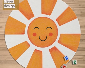 May include: A round rug featuring a smiling sun design with orange rays and a white background. The sun has rosy cheeks and a happy expression. The rug has the text "quite clever design" in the upper left corner. Small alphabet blocks are scattered on the wooden floor.