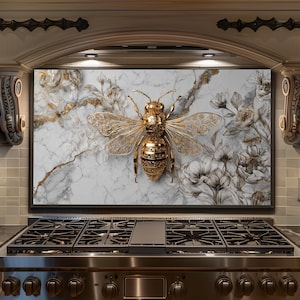 May include: A decorative kitchen backsplash featuring a large, golden bee with intricate details. The bee is set against a backdrop of white marble with gold veining and floral patterns. The overall design is elegant and luxurious.