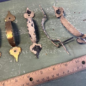 May include: Assortment of antique door handles with a distressed white paint finish and two brass handles with a decorative design.