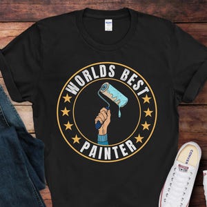 May include: Black t-shirt with a white circle graphic that says "Worlds Best Painter" and features a paint roller with blue paint dripping from it.