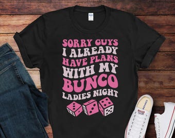 May include: Black t-shirt with pink text that reads "Sorry guys I already have plans with my Bunco Ladies Night". The shirt also features three pink dice.