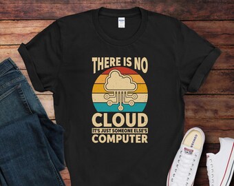 May include: Black t-shirt with the text "THERE IS NO CLOUD IT'S JUST SOMEONE ELSE'S COMPUTER" in a retro design. The graphic features a cloud and circuit board design with a sunset background. A pair of jeans and sneakers are in the image.