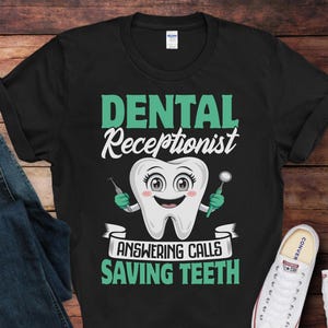 May include: Black t-shirt with the words "Dental Receptionist" in white and green. A cartoon tooth with a smiling face holds dental tools. The text "Answering Calls Saving Teeth" is below the tooth.