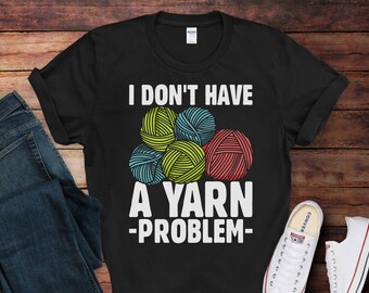 May include: Black t-shirt with white text that reads "I don't have a yarn problem."  The text is surrounded by colorful balls of yarn.