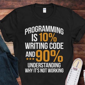 May include: Black t-shirt with white text that reads "PROGRAMMING IS 10% WRITING CODE AND 90% UNDERSTANDING WHY IT'S NOT WORKING".