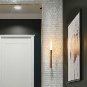 Peut inclure: Une petite salle de bain avec des murs vert foncé et des carreaux de métro blancs. Un lavabo en porcelaine blanche avec des robinets dorés est posé sur un comptoir en bois foncé. Le comptoir a une étagère inférieure avec un panier tissé et des serviettes.