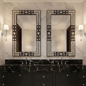 May include: A luxurious bathroom vanity with two large decorative mirrors. The mirrors have ornate frames with black and white accents. The vanity features a black marble countertop and dark wood cabinets with silver knobs. The walls and floor are white marble.