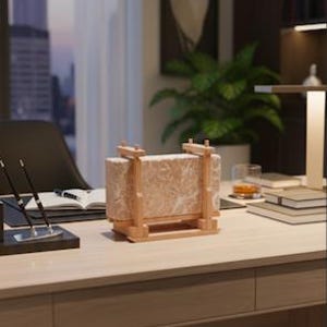 May include: A rectangular Himalayan salt lamp, encased in a light wood frame, sits on a wooden desk. The lamp has a pinkish hue and is illuminated. The desk is in an office setting with a view of a city skyline.